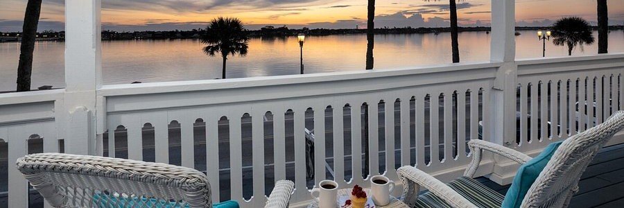 Waterfront porch at Bayfront Westcott House in St Augustine, Florida, overlooking Matanzas Bay during a colorful sunset.