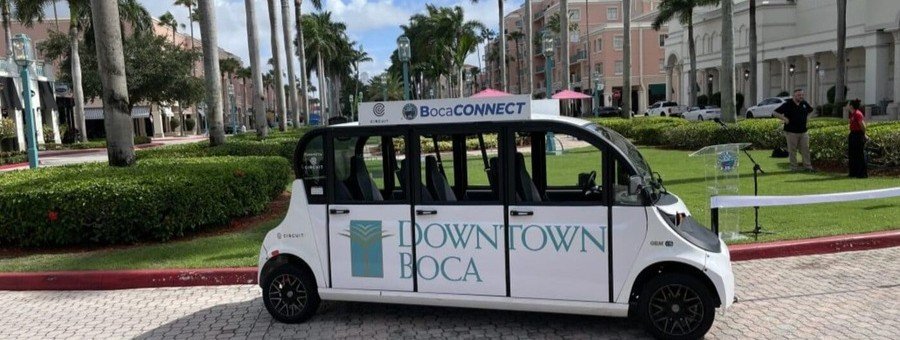 BocaConnect electric shuttle in downtown Boca Raton Florida providing local transportation near shops and palm-lined streets