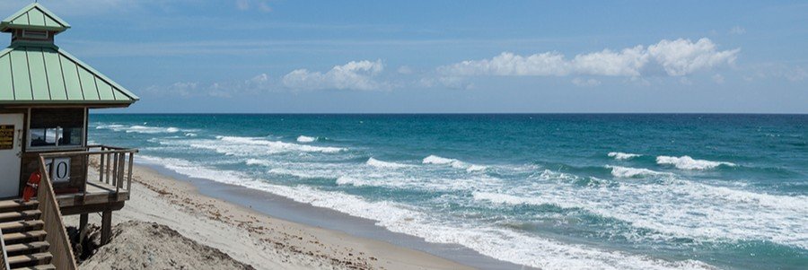 Boca Raton Beach Park Florida with sandy shoreline, rolling Atlantic waves, and lifeguard tower under blue sky