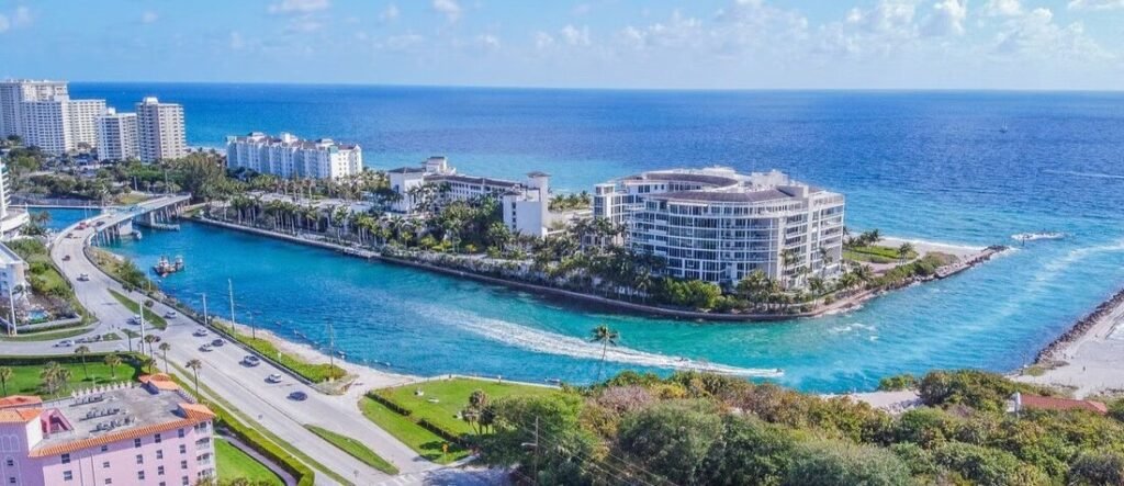 Aerial view of Boca Raton Florida coastline with turquoise inlet, luxury waterfront condos, palm trees, and Atlantic Ocean