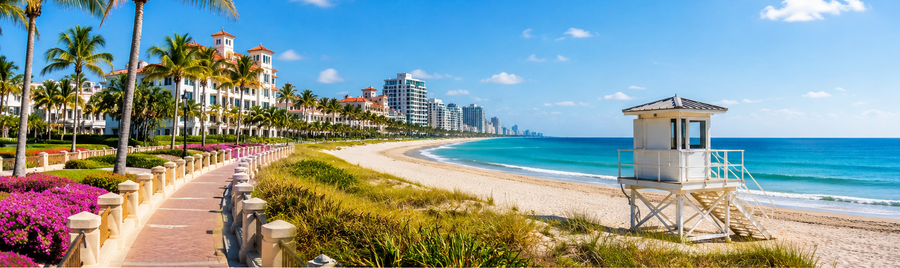 West Palm Beach Florida with palm trees, turquoise ocean, beachfront buildings and a lifeguard tower on a sunny day.