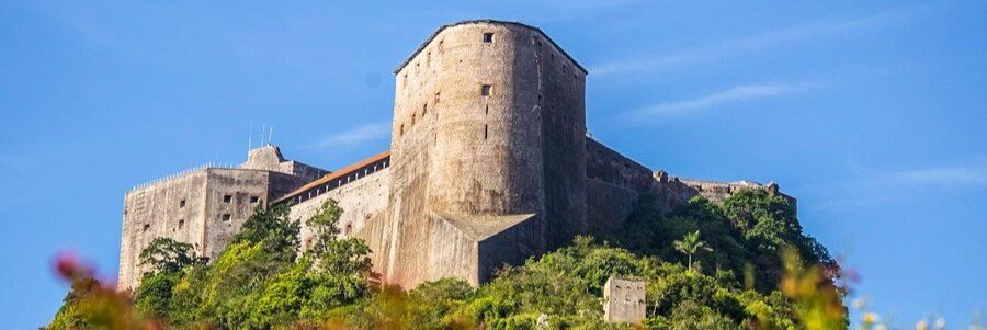 Massive stone walls and towers of Citadelle Laferrière rising above the green mountains near Milot, Haiti.