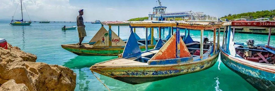 Colorful wooden water taxis moored in clear turquoise water along the coast of Haiti.
