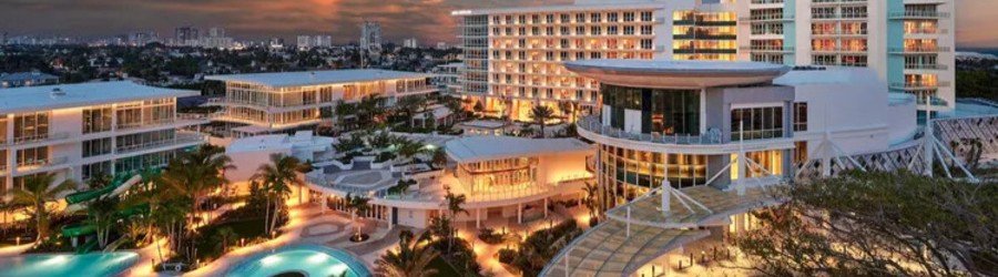 Conrad Fort Lauderdale Beach resort illuminated at sunset with luxury pools and modern oceanfront accommodations.