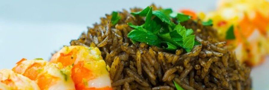 Haitian diri ak djon djon black mushroom rice served with shrimp, vegetables, and fresh herbs.