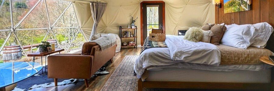 dome-suite-domes-loreto-unique-glamping-romantic-stay | Beach Travel Destinations Interior of Dome Suite Domes in Loreto, Mexico showing a modern glamping dome with a cozy bed, large windows, natural light, wood flooring, and comfortable seating area designed for a romantic stay