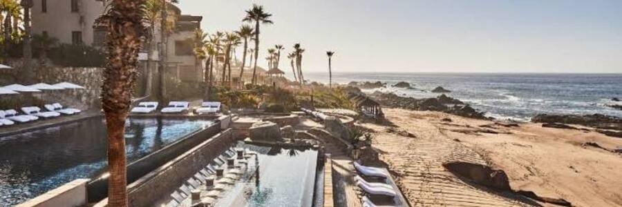 Oceanfront pools and lounge chairs at Esperanza, Auberge Resorts Collection, beside the rocky Los Cabos coastline.