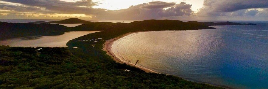 Aerial sunset view of a crescent-shaped Caribbean beach and surrounding hills in Culebra, Puerto Rico
