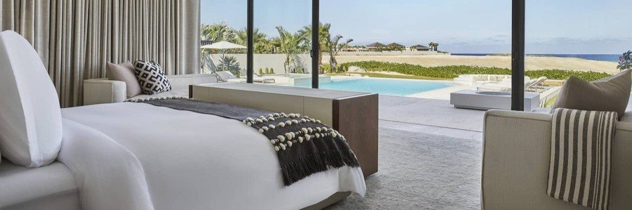 Luxury oceanfront villa bedroom at Four Seasons Resort Los Cabos at Costa Palmas featuring a modern interior, large glass doors, private pool, and direct views of the beach and Sea of Cortez.