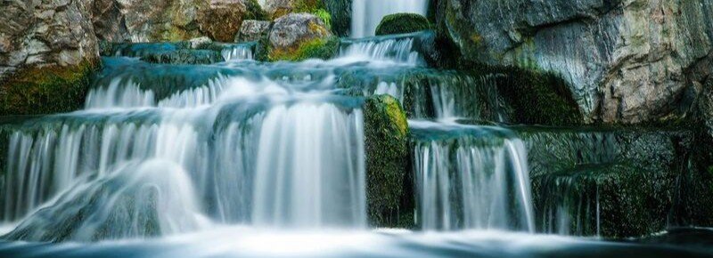Hidden waterfall cascading over mossy rocks in lush jungle setting in French Polynesia