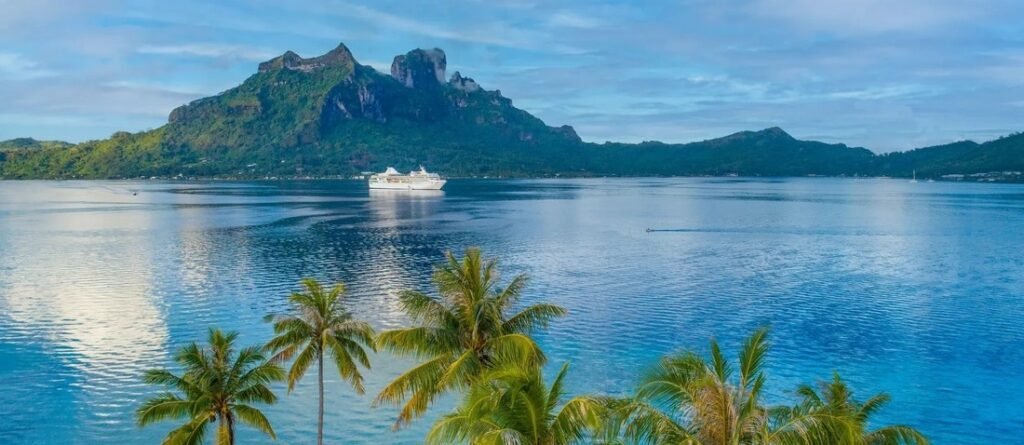 French Polynesia lagoon with mountain view, cruise ship, and palm trees