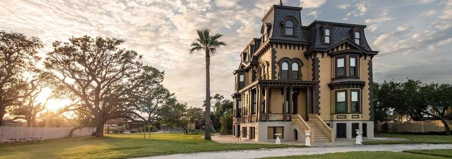 Fulton Mansion State Historic Site in Rockport Texas at sunset with oak trees and palm tree.
