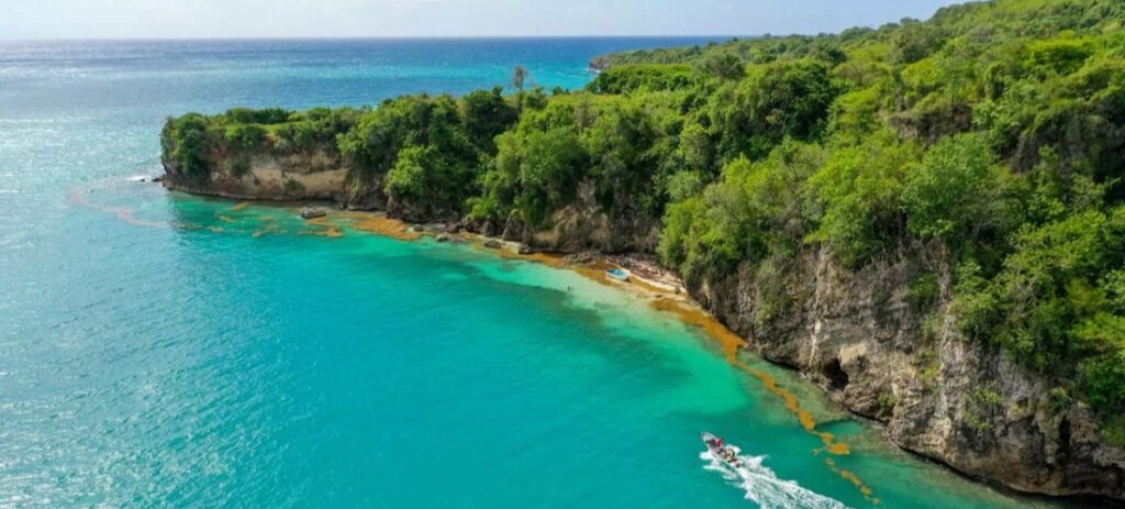 Aerial view of turquoise water and forested cliffs along Haiti’s coastline