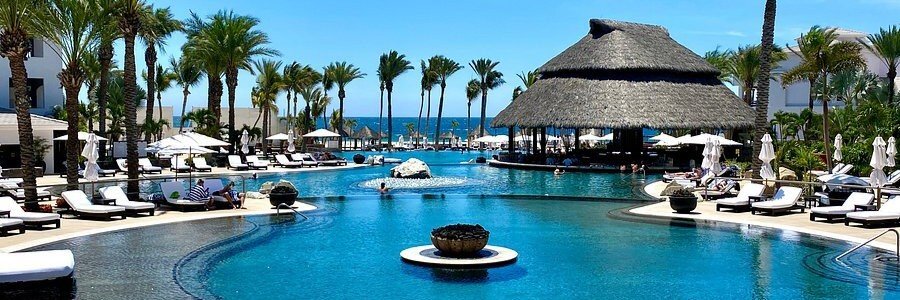 Luxury resort pool at Hilton Vacation Club Cabo Azul Los Cabos with palm trees, ocean views, lounge chairs, and tropical architecture.