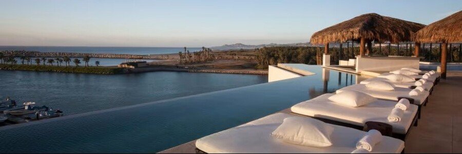 Infinity pool at Hotel El Ganzo Adults Only overlooking the marina and ocean with luxury lounge beds and sunset lighting.