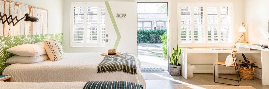 Bright and modern guest room at Hotel Palms Jacksonville Beach with comfortable beds, natural light, and coastal-inspired décor.