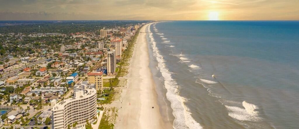 Aerial sunset view of Jacksonville Beach Florida with oceanfront hotels, sandy coastline, and Atlantic Ocean waves.