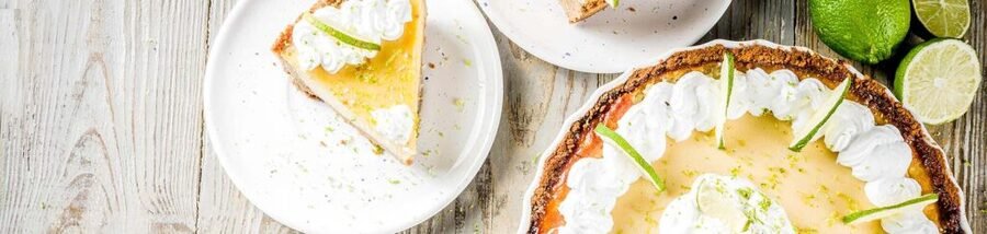 Key lime pie with whipped cream and fresh lime zest served on white plates