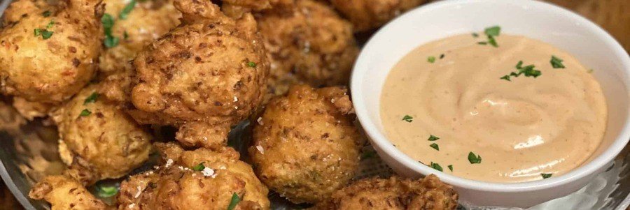 Golden brown conch fritters served with creamy dipping sauce at a seafood restaurant in Key West Florida.