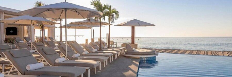 Luxury pool deck at Le Blanc Spa Resort Los Cabos with oceanfront lounge chairs, umbrellas, and calm coastal scenery.