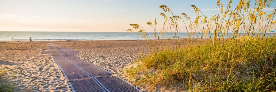 Mobi-mat beach access mat leading over sand dunes toward the ocean at Main Beach Park on Amelia Island Florida during sunrise.