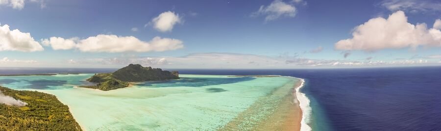 Aerial view of Maupiti island with turquoise lagoon, barrier reef, and deep blue ocean in French Polynesia
