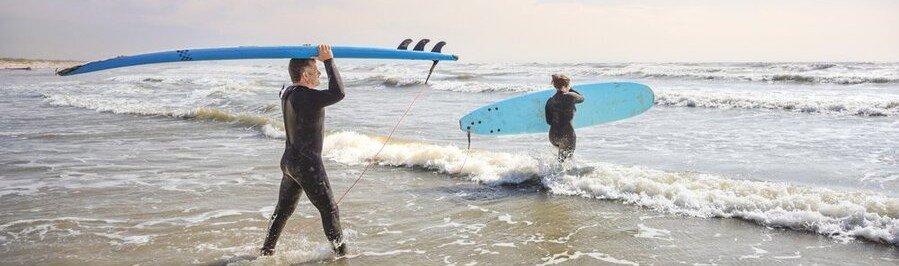 Surfers carrying boards into Gulf waves at Mustang Island near Port Aransas Texas.