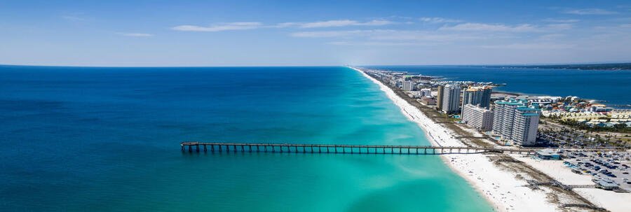 Aerial view of Navarre Beach Florida with fishing pier, white sand shoreline, and emerald Gulf Coast water