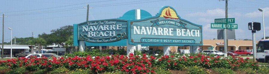 Welcome sign at Navarre Beach Florida with coastal flowers and Gulf Coast scenery