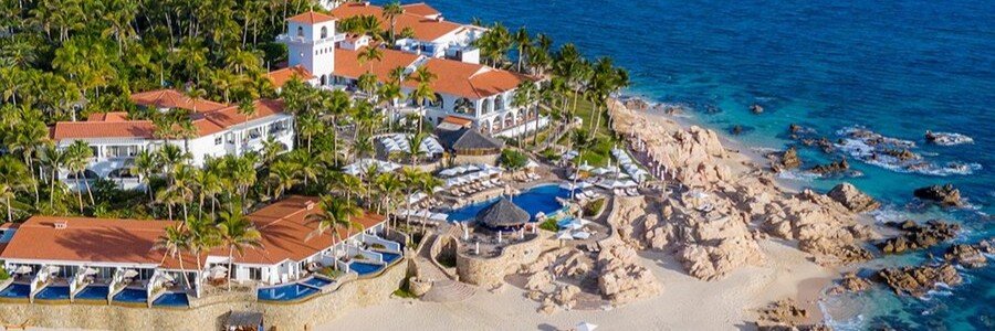 Aerial view of One&Only Palmilla resort in Los Cabos with rocky coastline, luxury pools, tropical landscaping, and beachfront villas.
