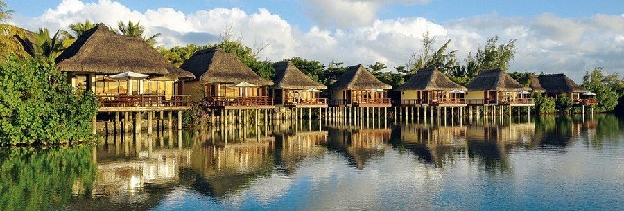 Overwater bungalows reflecting on calm lagoon water at a tropical resort