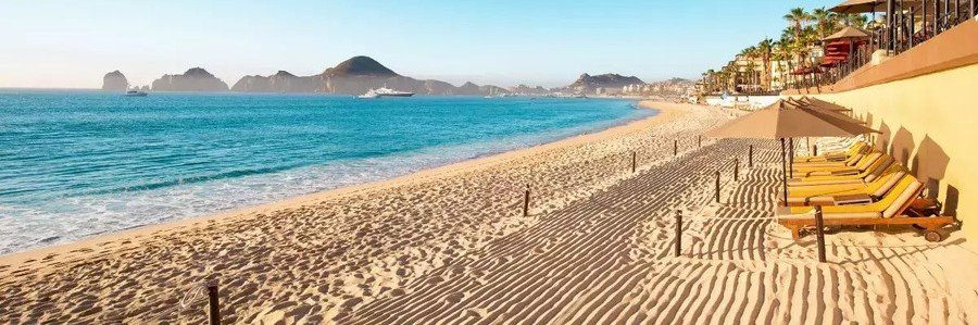 Cabo Beaches at Palmilla Beach with golden sand, blue water, shaded loungers, and distant coastal cliffs