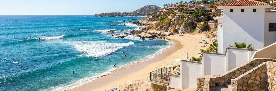 Cabo Beaches at Playa Acapulquito with surfers, rolling waves, golden sand, and hillside homes