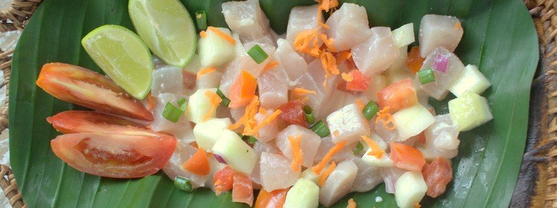 Poisson cru with raw fish, coconut milk, lime, and fresh vegetables on banana leaf