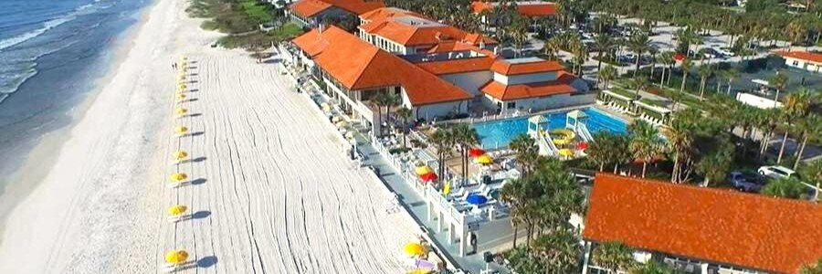Aerial view of Ponte Vedra Inn & Club featuring oceanfront pools, palm trees, and a pristine sandy beach.