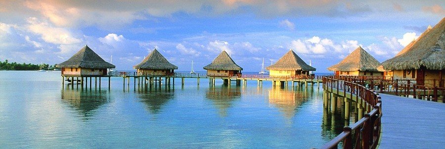 Overwater bungalows in Rangiroa lagoon with wooden walkway and calm water