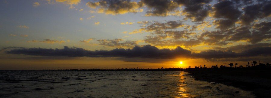Sunset over Aransas Bay at Rockport Beach with golden sky and calm water.