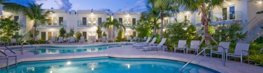 Tropical resort style pool at Santa Maria Suites in Key West surrounded by palm trees and luxury suites.