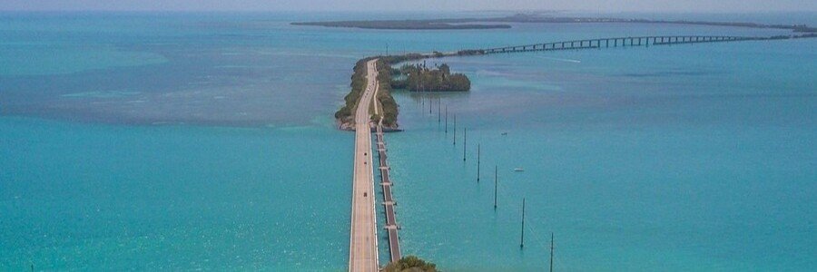 Aerial wide-angle view of the Seven Mile Bridge and Overseas Highway cutting through the bright turquoise waters of the Florida Keys.