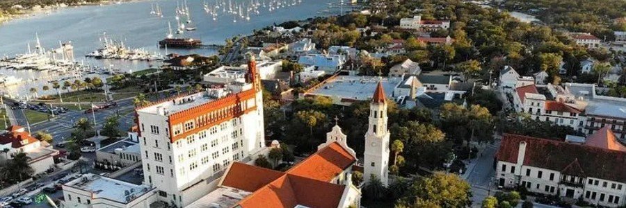 Aerial view of historic St Augustine, Florida, showing the city skyline, church towers, waterfront marina, and Spanish colonial architecture near Matanzas Bay.