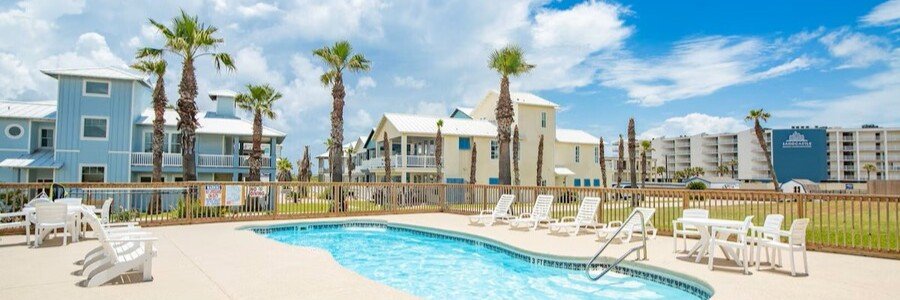 Swimming pool at Sunrise Villas Condos surrounded by colorful beach-style buildings in Port Aransas, Texas.