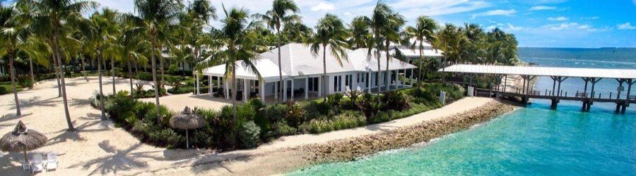 Luxury beachfront cottages at Sunset Key Cottages near Key West surrounded by palm trees and turquoise water.