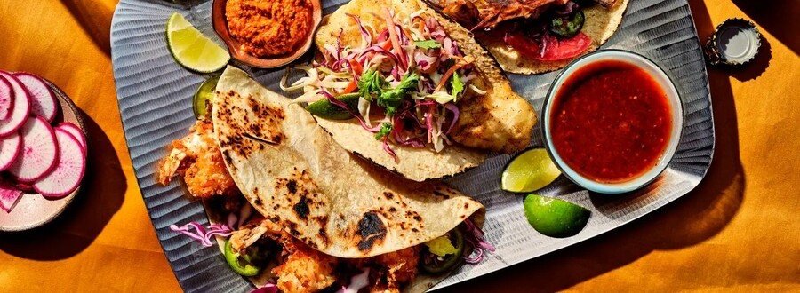 Seafood tacos from Taco George’s in Todos Santos Mexico with fresh toppings, salsa, lime wedges, and colorful Baja coastal flavors