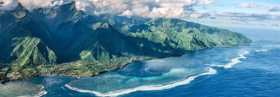 Tahiti coastline with lush mountains, reef, and lagoon from aerial view