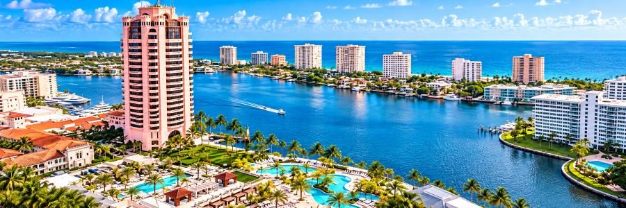 Pink luxury resort tower overlooking turquoise swimming pools, palm-lined grounds, a scenic waterway, and the Atlantic Ocean.