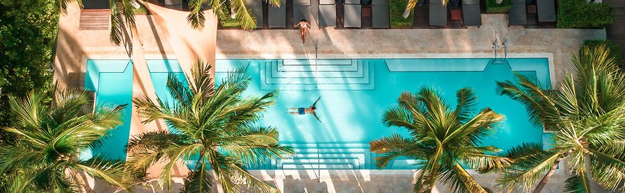 Aerial drone view of the luxury turquoise pool at The Setai Miami Beach surrounded by palm trees and lounge chairs.