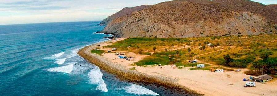 Aerial view of Todos Santos coastline in Baja California Sur Mexico with sandy beach, ocean waves, desert hills, and scattered campers
