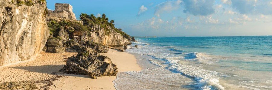 tulum-mayan-ruins-beach | Beach Travel Destinations Coastal scene with a sandy beach, rugged cliffs, and a fortress perched above the turquoise sea.
