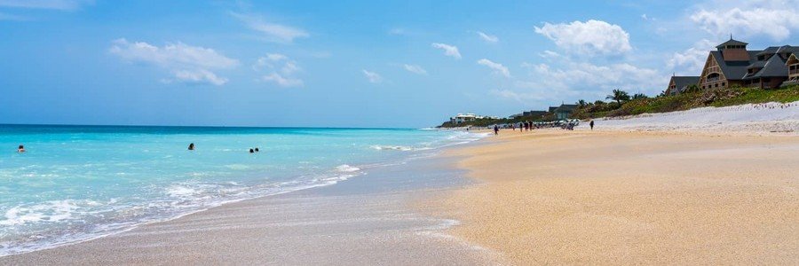 Swimmers in the turquoise Atlantic Ocean along the wide sandy shore of Vero Beach Florida near oceanfront resorts.