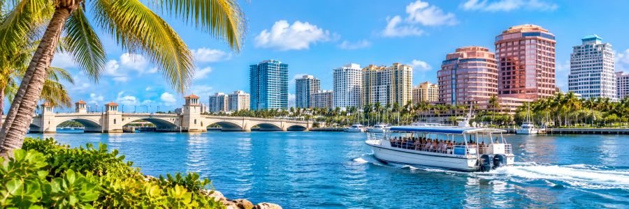 Sightseeing boat cruising the Intracoastal Waterway with the  skyline, bridge, and palm trees in the background